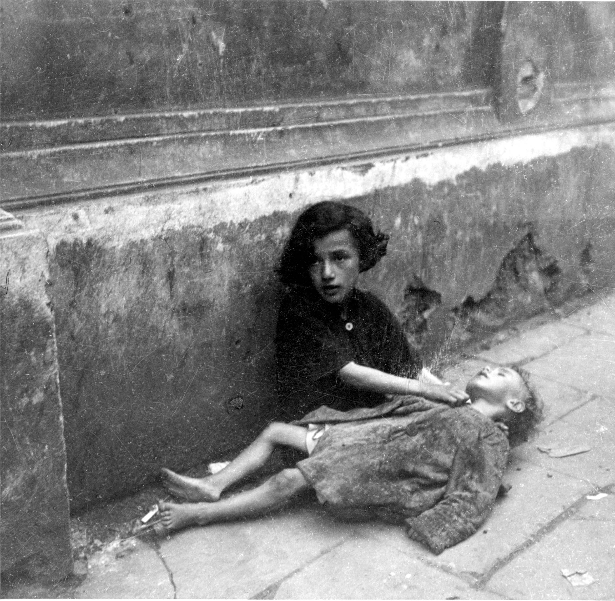 Starving children on the pavement in the ghetto, Warsaw, Poland.